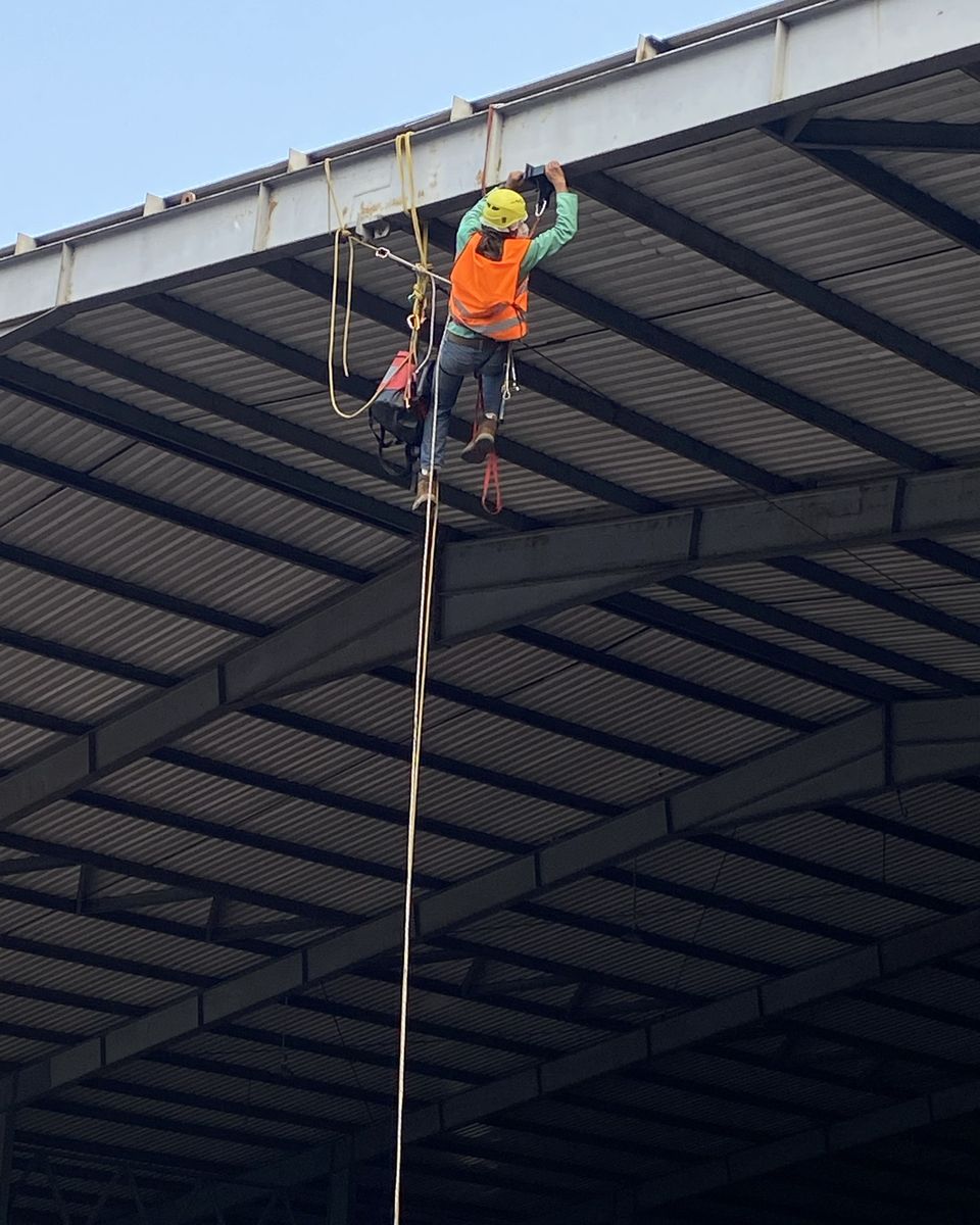 Técnico de Vertika colgado del techo de las bahías de carga durante la instalación de la línea de vida