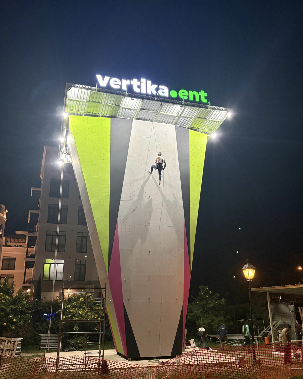 El Muro, muro de escalada al aire libre de Vertika Entertainment en Ciudad Cayalá, iluminado de noche con una escaladora en la pared